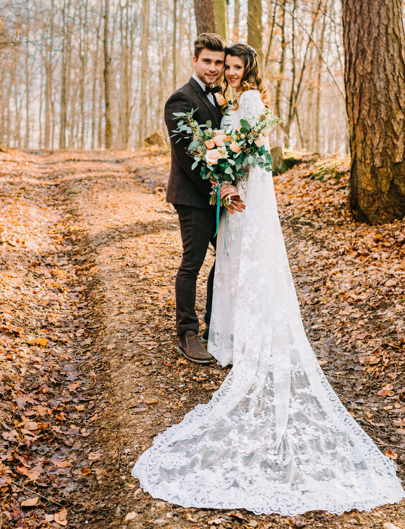 The bride was wearing a lace sheath wedding dress with a cape and a half updo, the groom was wearing a brown tweed three piece suit with a bow tie and brown shoes
