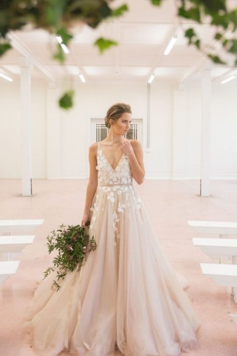 a blush tulle wedding dress with floral appliques on the bodice and a deep V-neckline