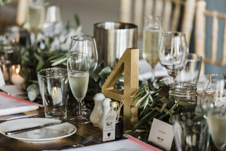 The wedding tables were styled with greenery, gold numbers, neutral cutlery and porcelain