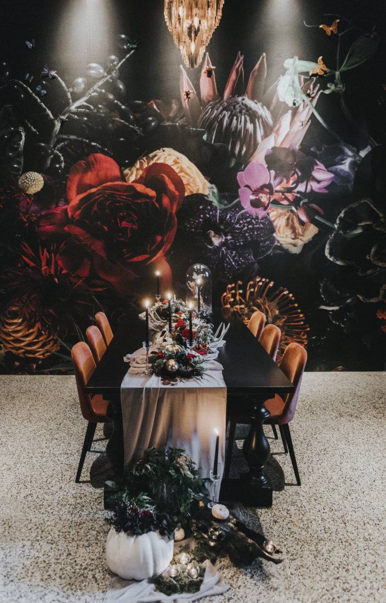 The wedding tablescape was styled with gilded pumpkins, greenery, bold blooms, black candles and antlers