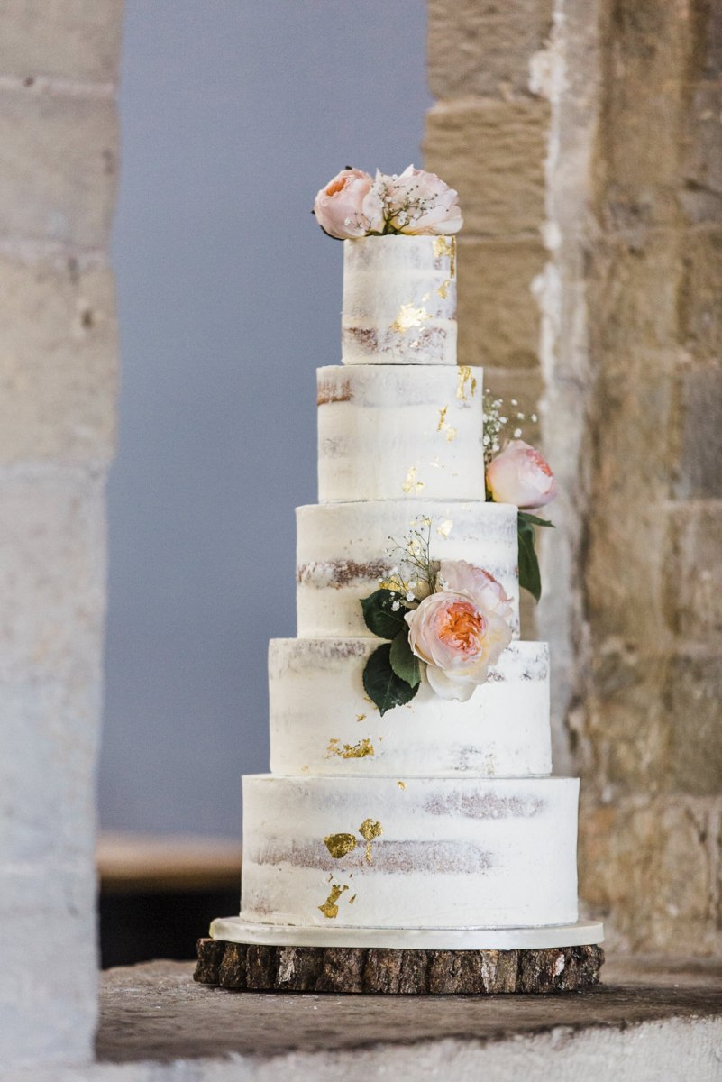 The wedding cake was naked, with gold leaf decor and pink blooms and foliage for a cozy feel