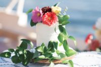 08 There was a small white wedding cake decorated with greenery and bright blooms