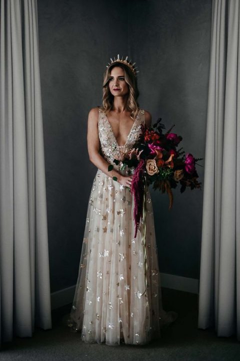 a sleeveless blush wedding dress with a plunging neckline, metallic stars and a crystal crown for a gorgeous look
