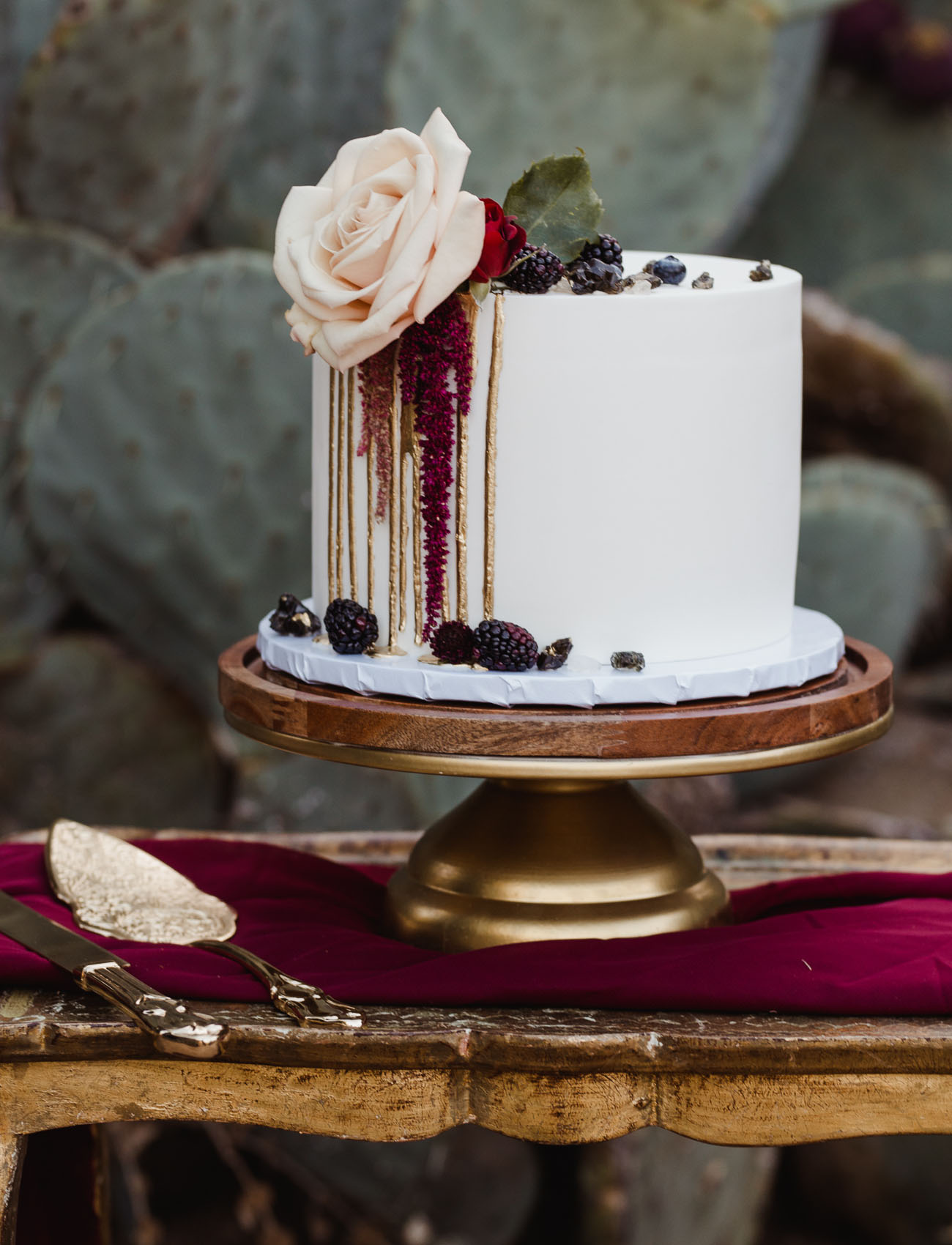 The wedding cake was a white one, with gold drip, blackberries, blush and red blooms