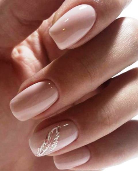 shiny blush nails with an accent on the ring finger with a white and gold glitter feather for a bride