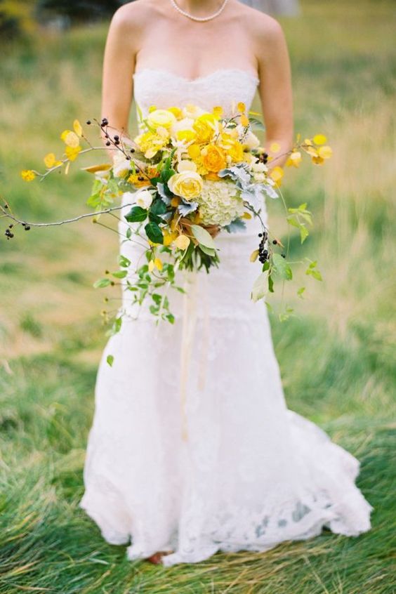 a bold marigold wedding bouquet with lush blooms, some fall ried leaves and fresh greenery for a fall wedding