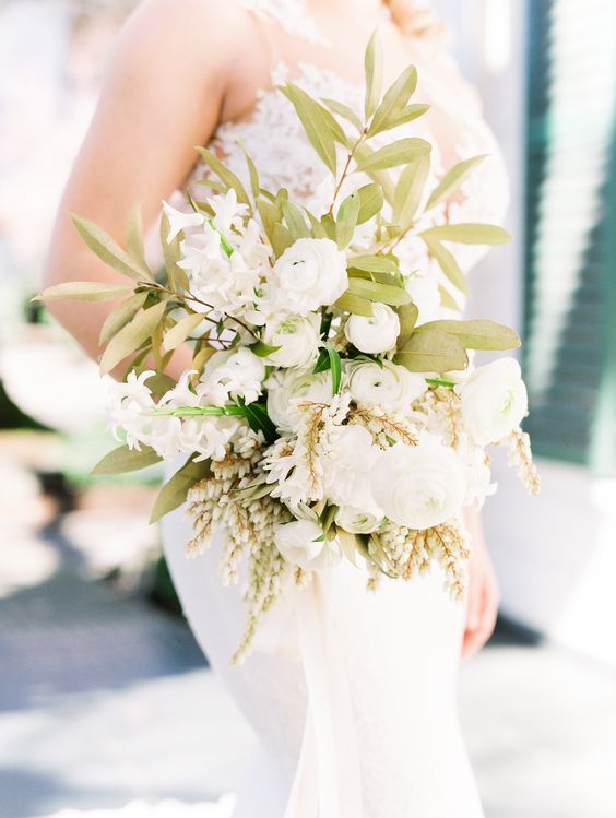 a chic white wedding bouquet with just some touches of foliage is a very stylish idea for a romantic bride