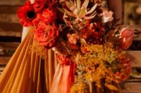 a deep red and rust wedding bouquet with fresh and dried blooms and herbs embraces the fall with its colors