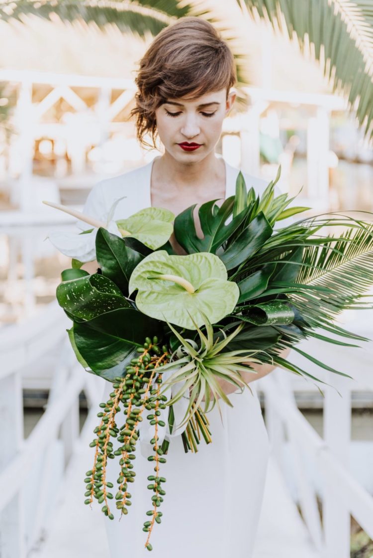a green tropical wedding bouquet with succulents, air plants and large monstera leaves for a modern bride