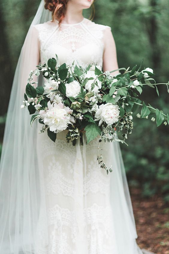 a romantic spring wedding bouquet of white blooms, blooming branches and some foliage