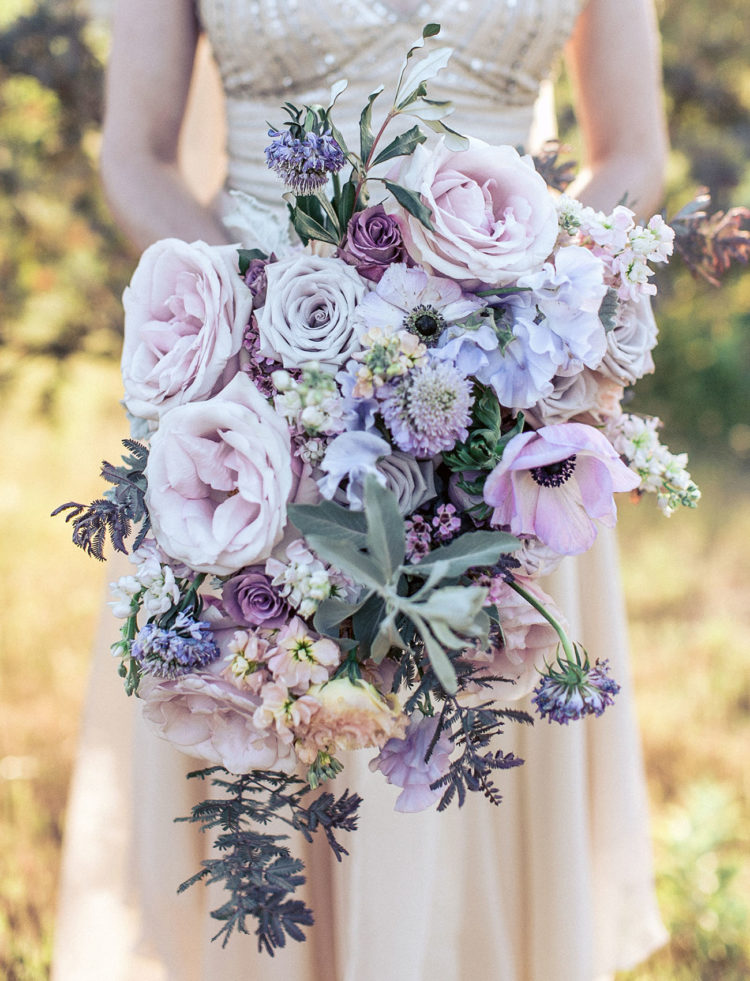 a tender lilac cascading wedding bouquet with lots of various blooms and some pale greenery for a spring bride