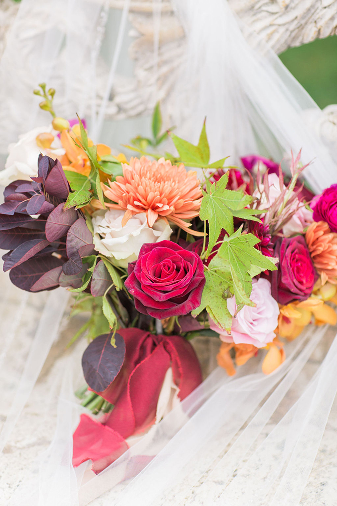 The wedding bouquet was done with deep red, orange, blush and white blooms, greenery and dark foliage