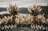 05 The ceremony space was done with moody blooms, pampas grass and textural greneery plus lots of candles