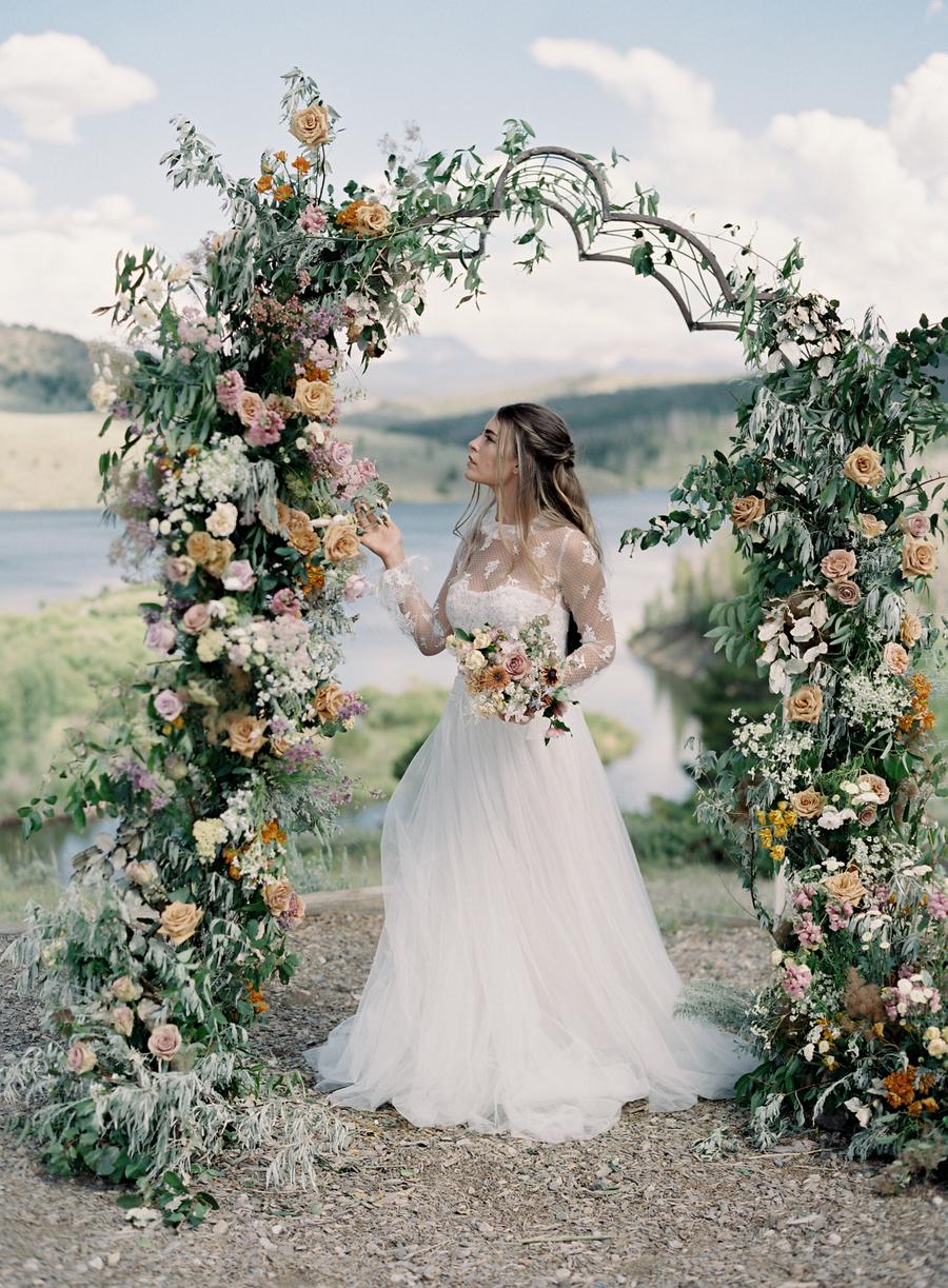 The second wedding dress was with an illusion neckline and illusion sleeves, and the wedding arch was done with lush blooms