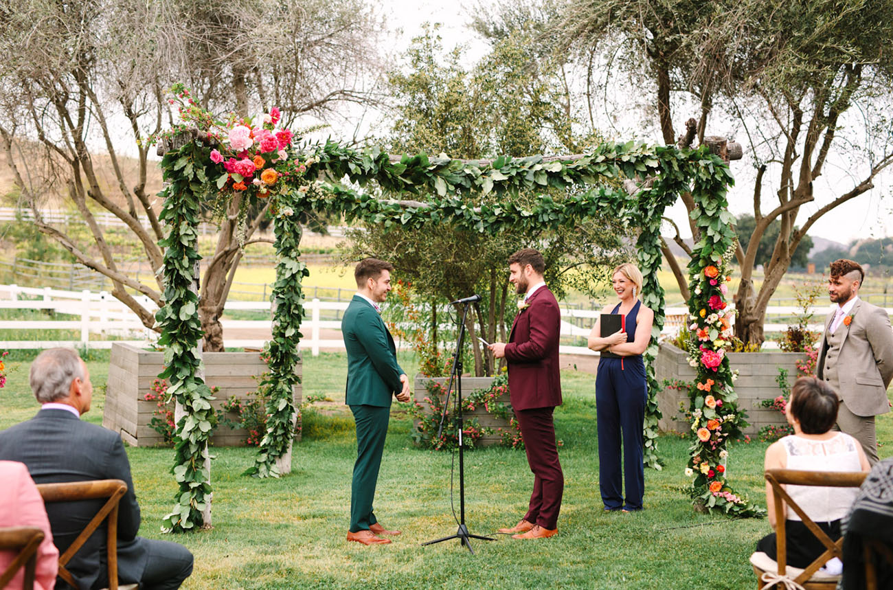 The wedding ceremony space was done with a lush greenery arch that was decorated with bright florals on one corner