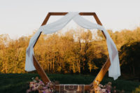 06 The wedding arch was done with white fabric, lush blooms and a boho rug