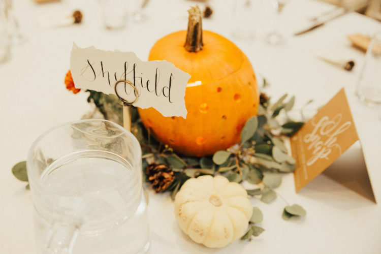 The centerpieces included white and orange pumpkins, greenery and pinecones