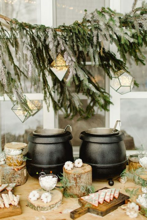 cozy and modern dessert table styling with tree stumps, evergreens and lights over and on the table