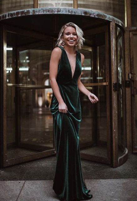 a forest green emerald maxi dress with thick straps and a plunging neckline plus statement earrings
