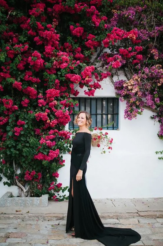 a black off the shoulder maxi dress with long sleeves, a thigh high slit, a train and black shoes for a super sophisticated look