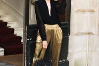a black semi sheer blouse, gold metallic pants, black shoes and a black bag are a lovely combo for NYE