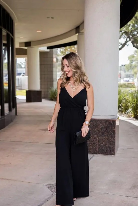 a black spaghetti strap jumpsuit with wideleg pants, a black clutch and a statement necklace