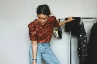 a catchy yet casual fall wedding guest look with a rust sequin top, bleached blue jeans, whimsical shoes with catchy heels