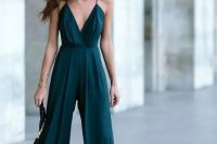 a dark green jumpsuit on spaghetti straps, with wideleg pants and a tassel clutch for a Christmas wedding