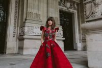 a fantastic red A-line dress with ruffle sleeves, a high neckline, a floral embellished bodice, a printed skirt, red shoes with pompoms