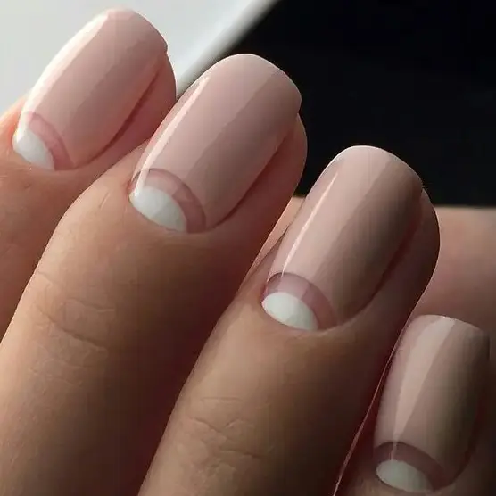 a fresh take on French manicure with half moon whites and light pink base is an edgy idea