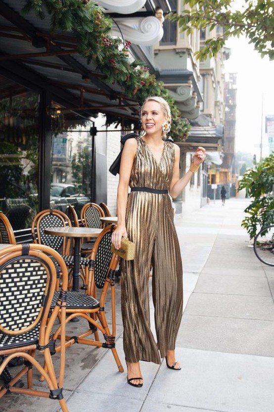 a gold metallic jumpsuit with a V-neckline and wide straps, black strappy shoes and a gold clutch for NYE