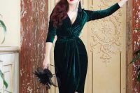 a gorgeous wrap emerald velvet dress with a plunging neckline, half sleeves, with buttons and black shoes and tassel earrings