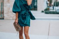 a green one shoulder mini dress with a single puff sleeve, a sash, nude heels and a metallic bag for a winter or fall wedding