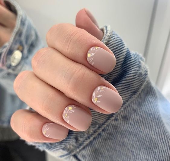 a nude wedding manicure with subtle botanical touches in white and gold is a very chic and cool idea