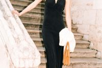 a refined NYE wedding guest look with a black maxi dress with lace trim, shiny shoes, an amber bag and a faux fur cover up