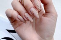 an ultra-modern wedding manicure with matte nude nails and gold abstract lines is a catchy idea for a modern bride