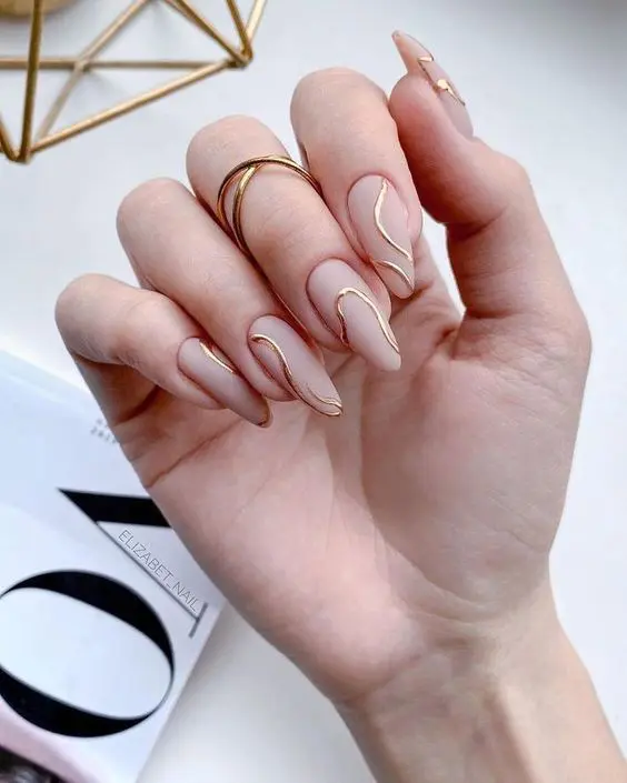 an ultra-modern wedding manicure with matte nude nails and gold abstract lines is a catchy idea for a modern bride