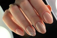 nude wedding nails with an accent on the ring finger, with a rhinestone flower, are a cool and pretty solution for a wedding