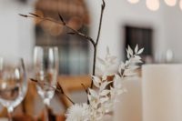03 a simple and chic wedding centerpiece of branches and dried blooms in a terrazzo plate is a cool idea