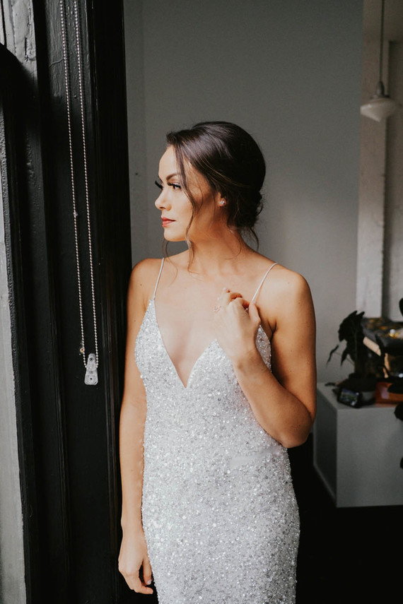 The bride was wearing a beautiful embellished sheath wedding dress with a deep neckline and spaghetti straps