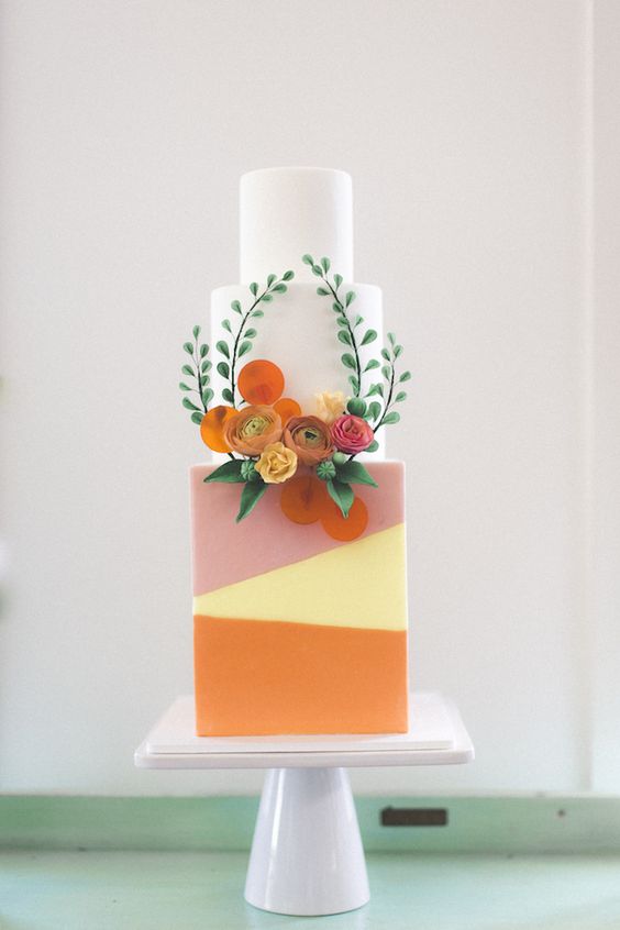 a modern and cute wedding cake with bright color blocking and natural and sugar blooms and greenery