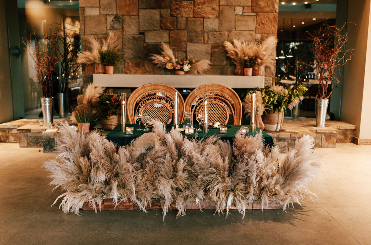 The sweetheart table was done with pampas grass, candles and bold blooms