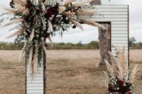 16 a Western-inspired wedding arch done with pampas grass, blush and burgundy blooms and a cowhide rug