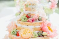 20 a naked wedding cake decorated with green, sherbet pink and gold blooms and strawberries