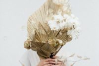 21 a unique wedding bouquet of gilded leaves, lunaria and white orchids features a very unusual structure