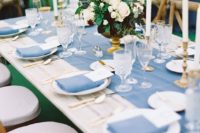 23 a chic tablescape with a pastel blue table runner, napkins, gold touches and white blooms and greenery