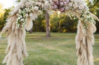 41 a lush wedding arch covered with pampas grass and blush and pink blooms on top