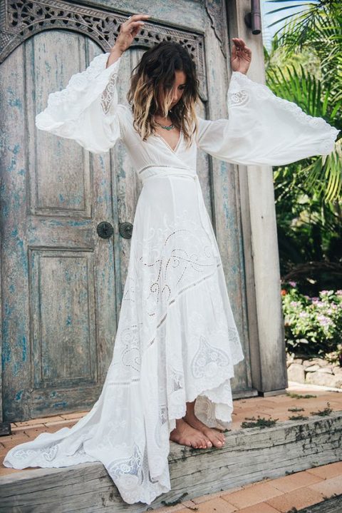 a boho wrap wedding dress by Spell with a high low skirt, a deep V neckline and bell sleeves plus lace inserts