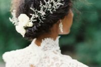 a messy and textural wedding updo with a twisted halo and some greenery and white blooms for an accent