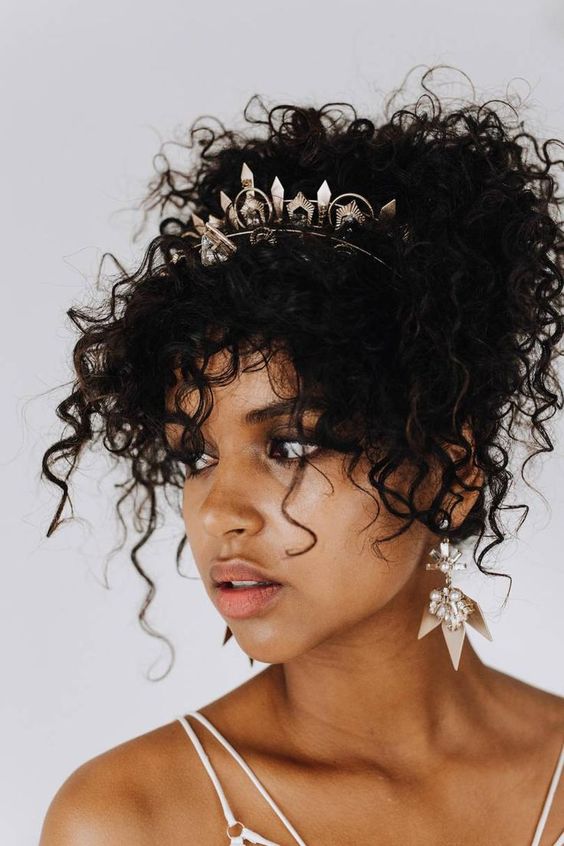 natural curls styled into an updo with many locks down accented with a trendy crystal headpiece